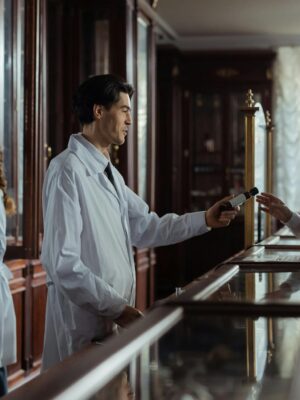 A pharmacist hands medication to a customer at a classic vintage pharmacy counter.