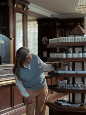 A pharmacist helps a customer in an old-fashioned pharmacy with wooden decor and vintage aesthetic.